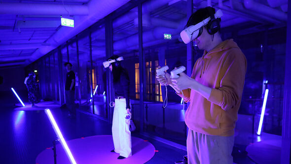 Personer använder VR-glasögon och handkontroller i en upplyst miljö.