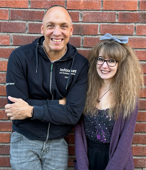 Man och kvinna ler mot kameran framför en tegelvägg.