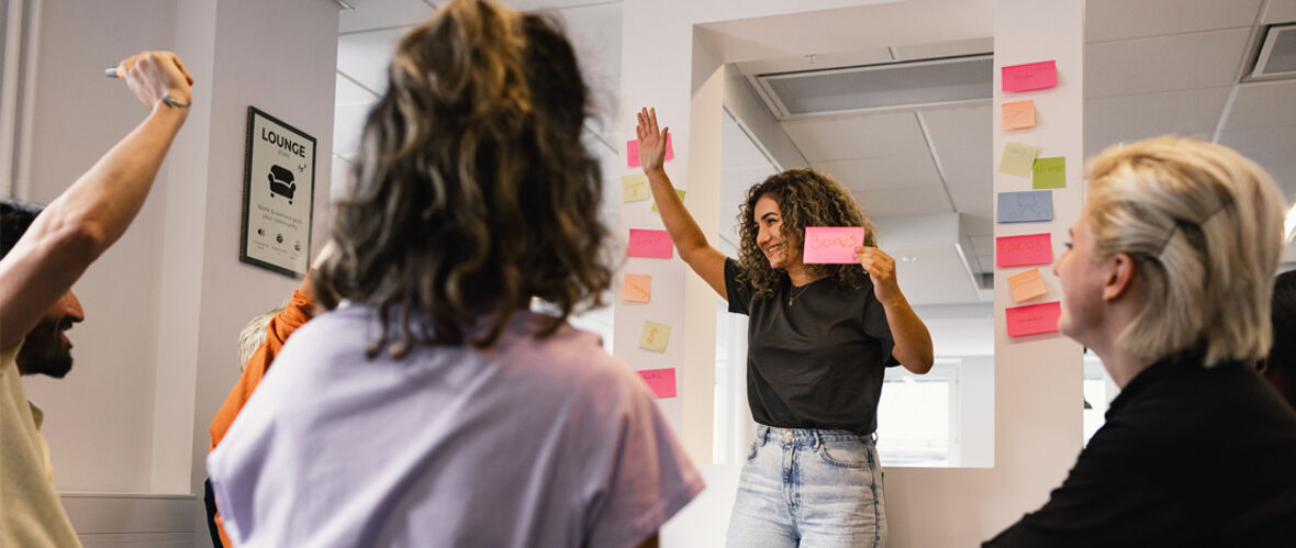 Grupp av kollegor deltar i en interaktiv workshop med post-it-lappar på väggen.