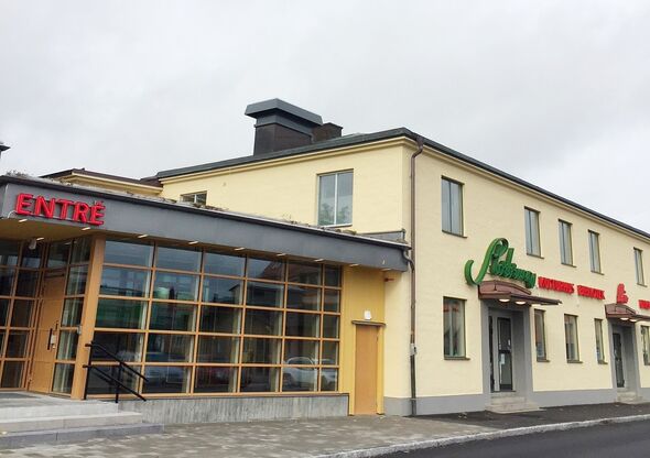 En byggnad i ljusgul puts och glas med neonskyltar.