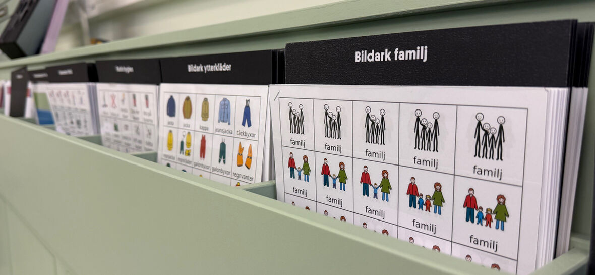 Hyllfack med bildstödskort där pictogram för familj och ytterkläder syns