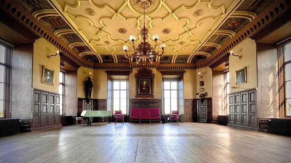 Storslagen historisk sal med utsmyckat tak, ljuskrona och stora fönster