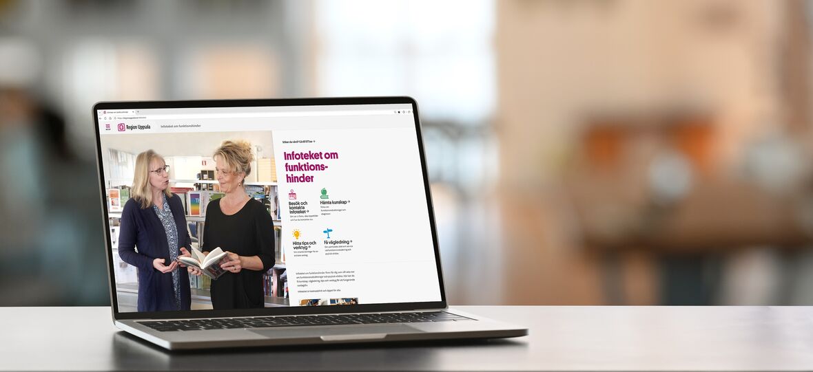Bärbar dator på bord visar två personer som bläddrar i en bok på en informationssida om funktionshinder