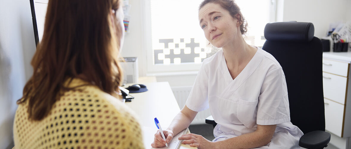 Vårdpersonal som samtalar med patient i mottagningsrum