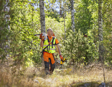 Man som går genom skogen med röjsåg på axeln. Foto: Patrik Svedberg