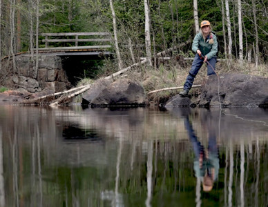 En bild från Grip on Lifes film "Inte bara fisk". En kvinna står vid ett vattendrag med ett fiskespö i handen. Foto: Bitzer Productions AB