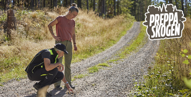 Två personer som tittar och känner på grusväg i skogen.