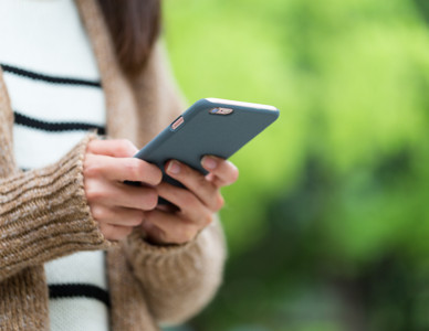 Närbild på händer som håller och använder en smartphone utomhus. Foto: Mostphotos