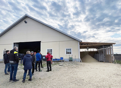 Grupp människor utanför en lantlig byggnad på en gård Grupp människor utanför en lantlig byggnad på en gård