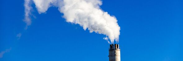 Rökpelare från industriskorsten mot klarblå himmel. 