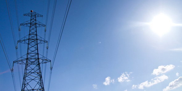 En högspänningsledning med solen i bakgrunden.